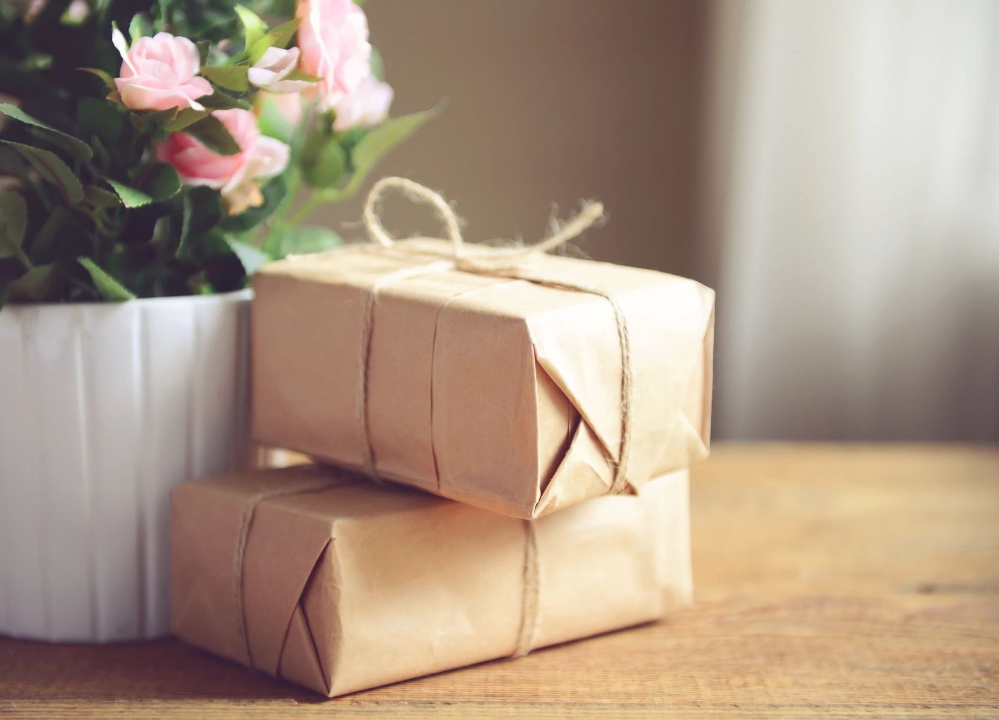 Parcels wrapped on a table next to some flowers in a white plant pot - Home Gifts & Accessories from C G Interiors in San Leandro, CA