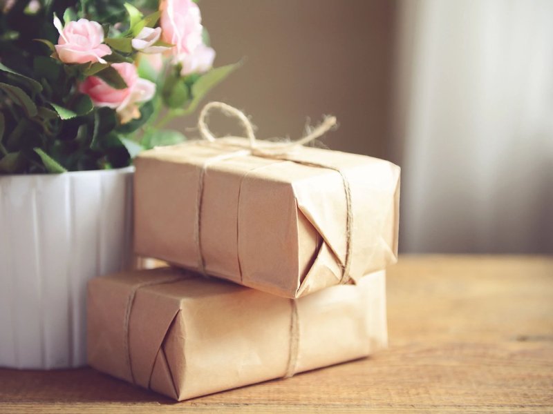 Parcels wrapped on a table next to some flowers in a white plant pot - Home Gifts & Accessories from C G Interiors in San Leandro, CA